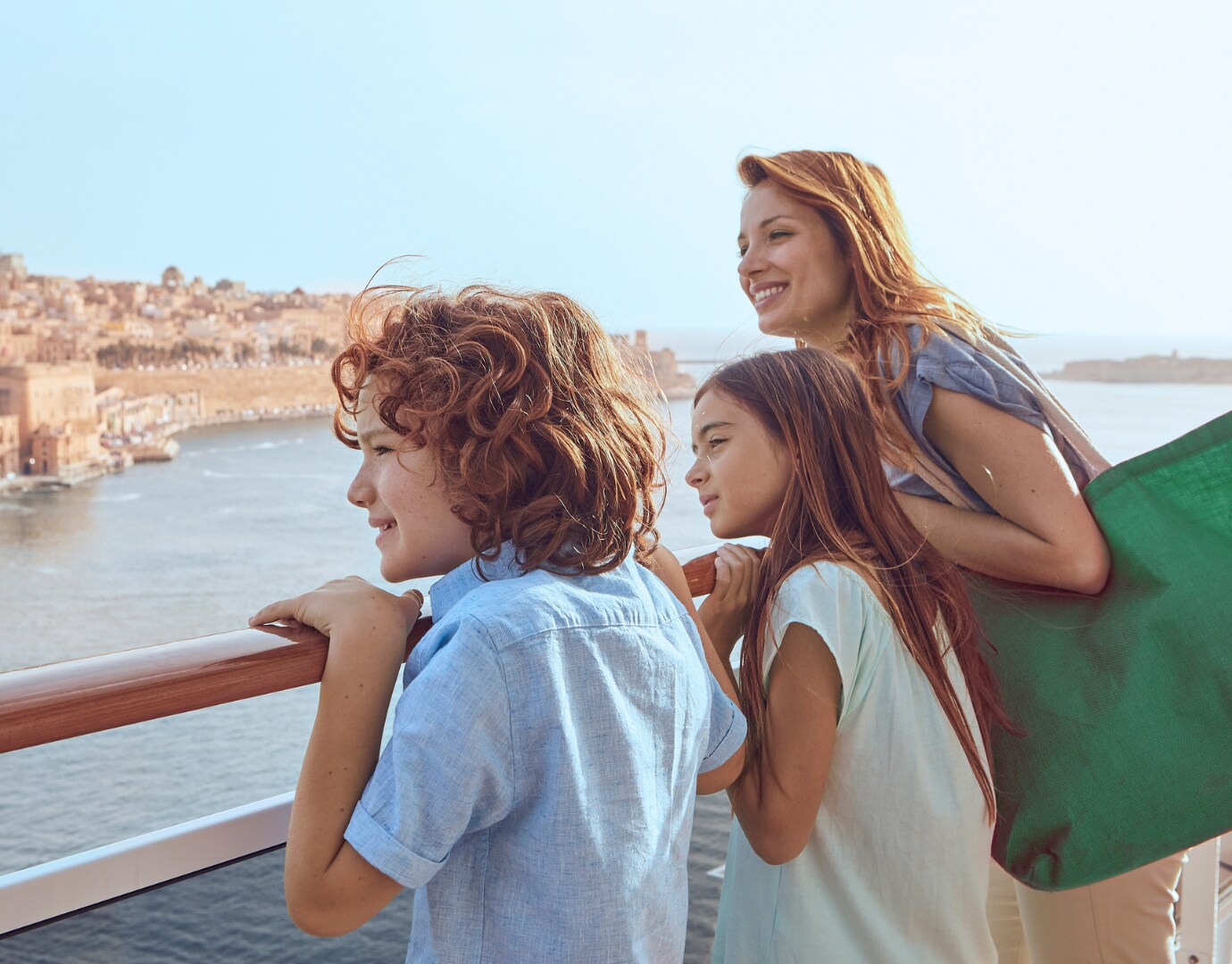 Family enjoying the view from a cruise ship balcony overlooking a coastal city | MSC Cruises