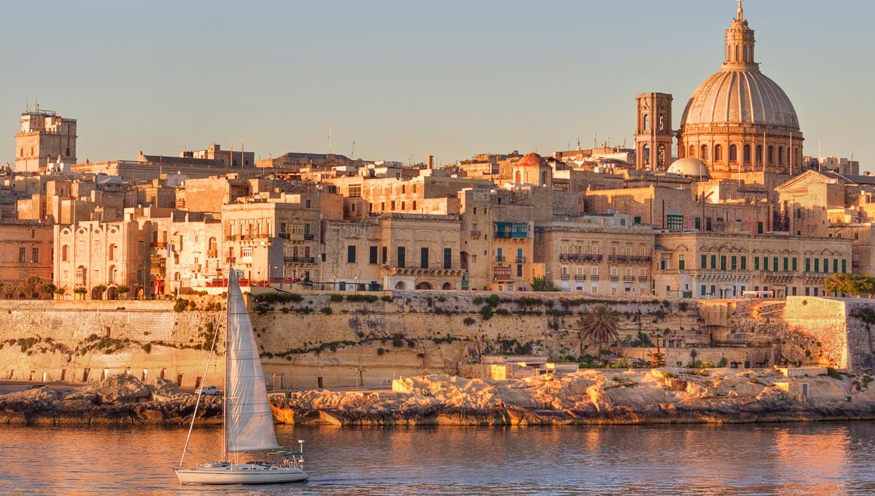 A sailboat gliding past the historic skyline of Valletta, Malta at sunset | MSC Cruises A sailboat gliding past the historic skyline of Valletta, Malta at sunset | MSC Cruises