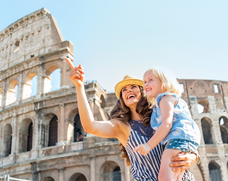 A mother holds her child in front of the Colosseum in Rome, pointing at the landmark | MSC Cruises
