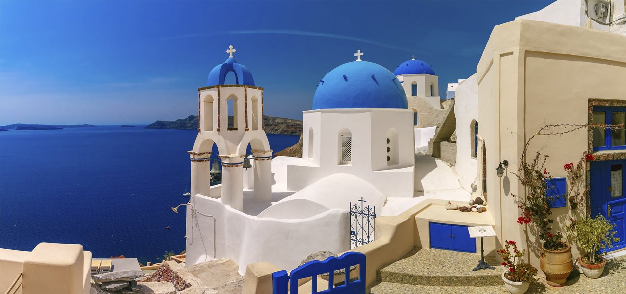 Whitewashed buildings with blue domes overlooking the Aegean Sea in Santorini | MSC Cruises