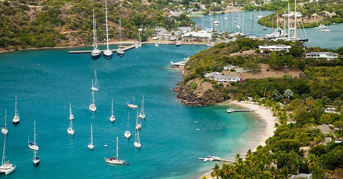 A scenic bay with anchored sailboats and lush greenery | MSC Cruises