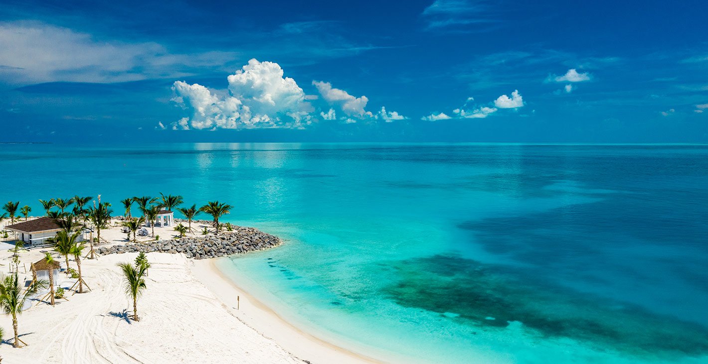 A pristine white sandy beach with turquoise waters and tropical palm trees | MSC Cruises