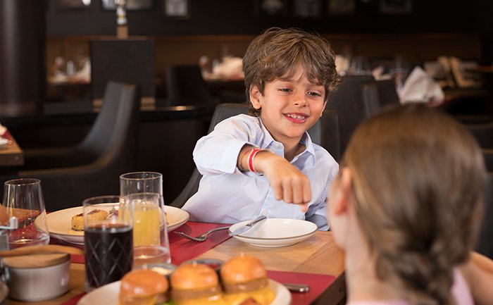 Children enjoying a family meal with burgers and drinks in an elegant onboard restaurant | MSC Cruises