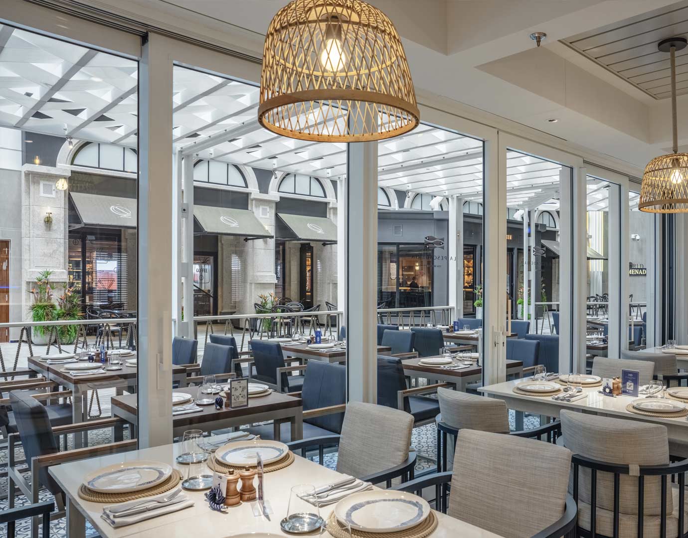 Elegant dining area with set tables and a view of a stylish promenade | MSC Cruises