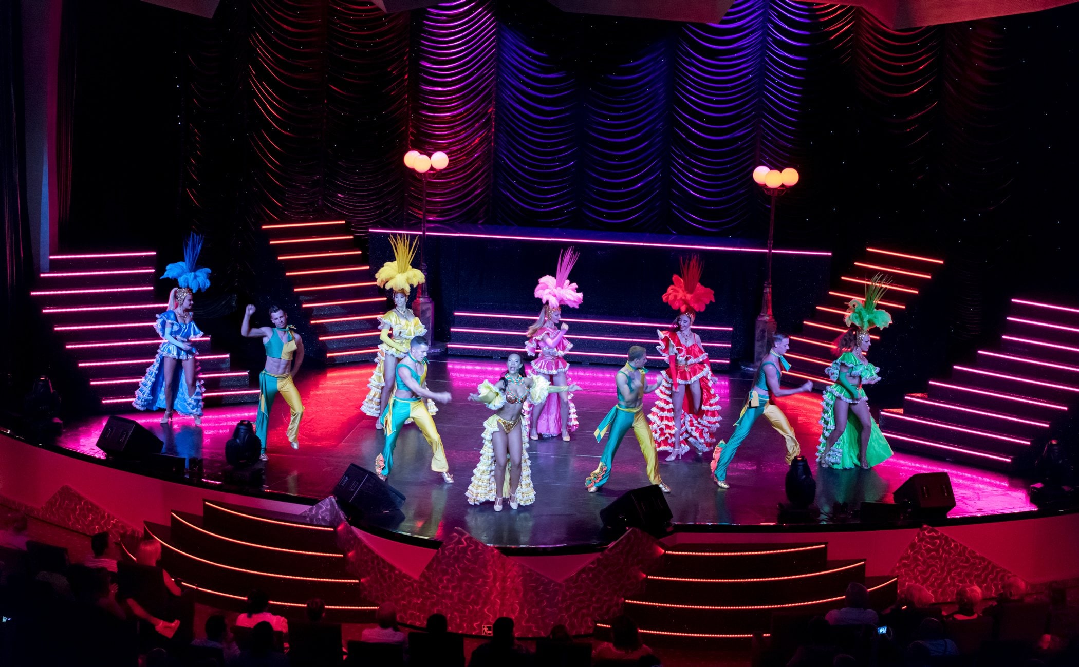 Vibrant theater performance with dancers in colorful costumes on a cruise ship stage | MSC Cruises Vibrant theater performance with dancers in colorful costumes on a cruise ship stage | MSC Cruises