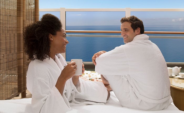 Couple in bathrobes enjoying coffee on a private balcony with ocean views | MSC Cruises