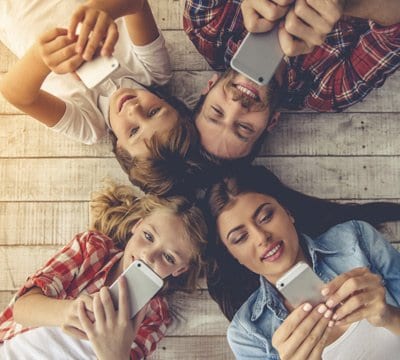 Group of friends using smartphones on a wooden deck | MSC Cruises Group of friends using smartphones on a wooden deck | MSC Cruises