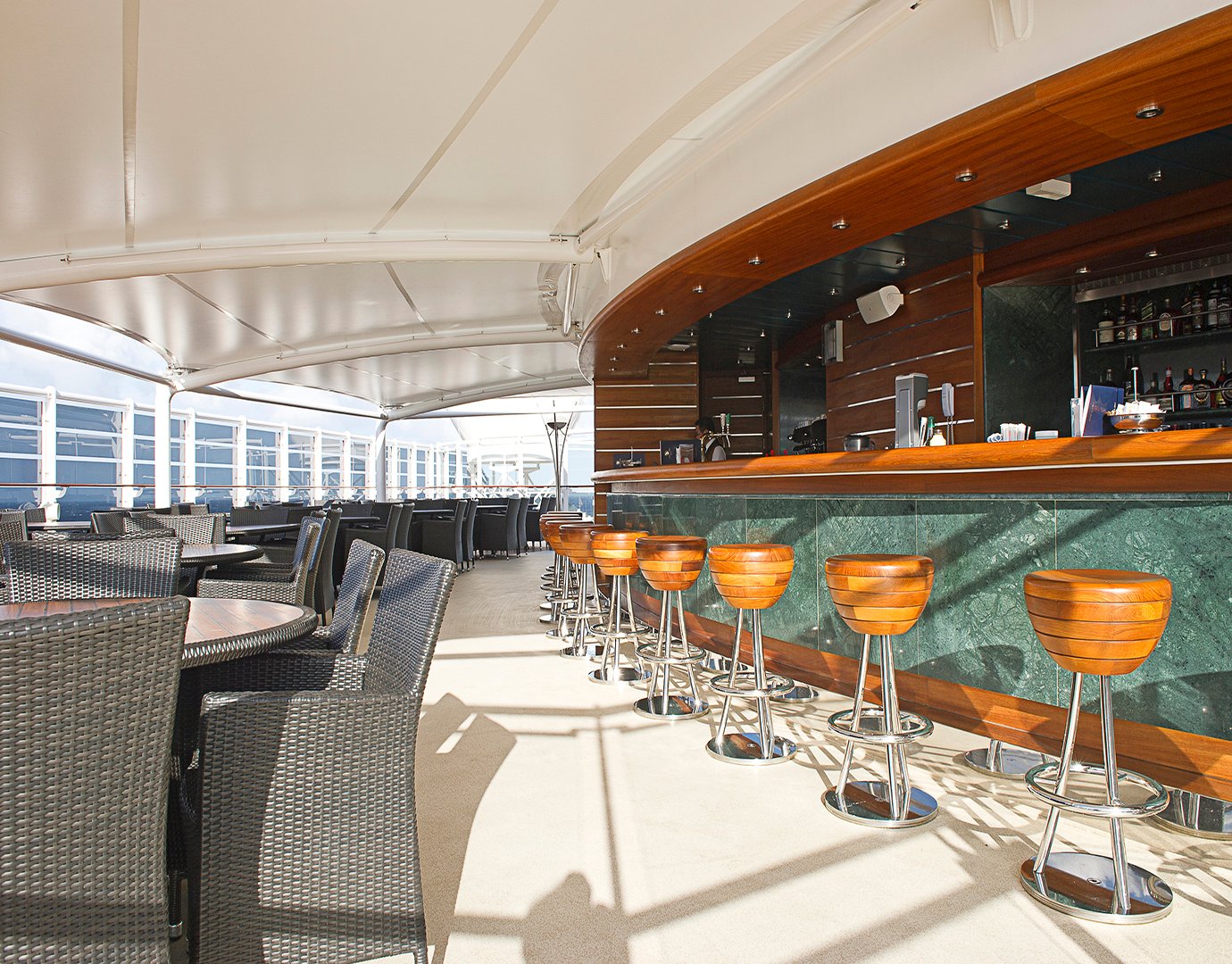 Outdoor bar with wooden stools and wicker seating on an MSC cruise ship | MSC Cruises Outdoor bar with wooden stools and wicker seating on an MSC cruise ship | MSC Cruises