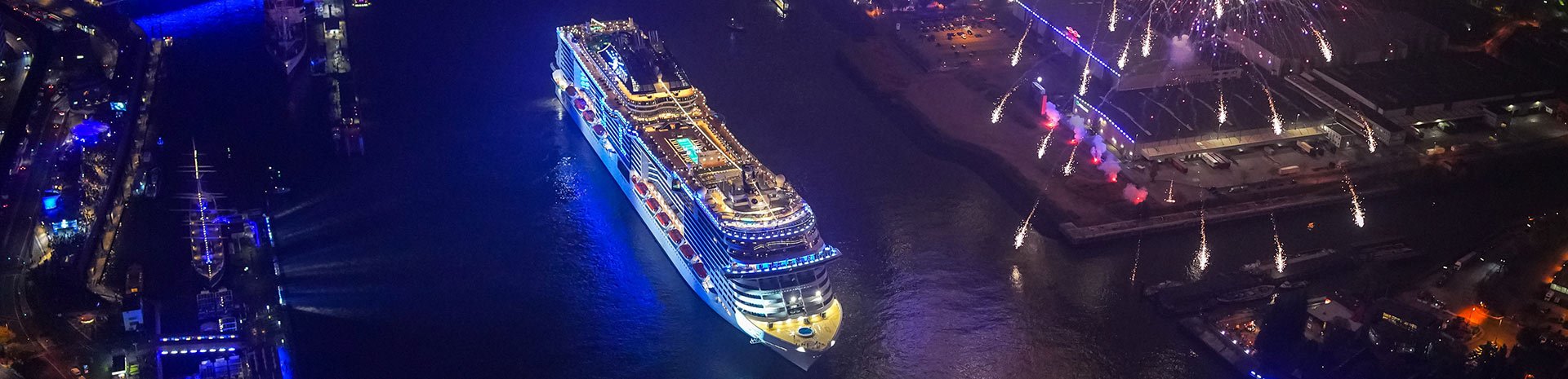 An illuminated MSC cruise ship with fireworks in a vibrant port at night | MSC Cruises An illuminated MSC cruise ship with fireworks in a vibrant port at night | MSC Cruises