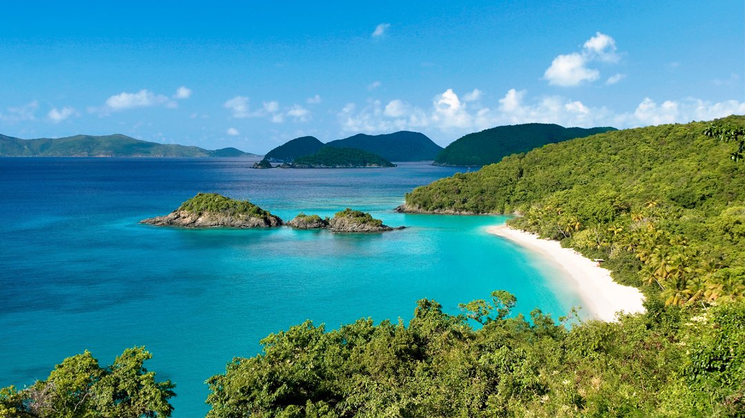 A pristine tropical beach with turquoise waters and lush green hills | MSC Cruises