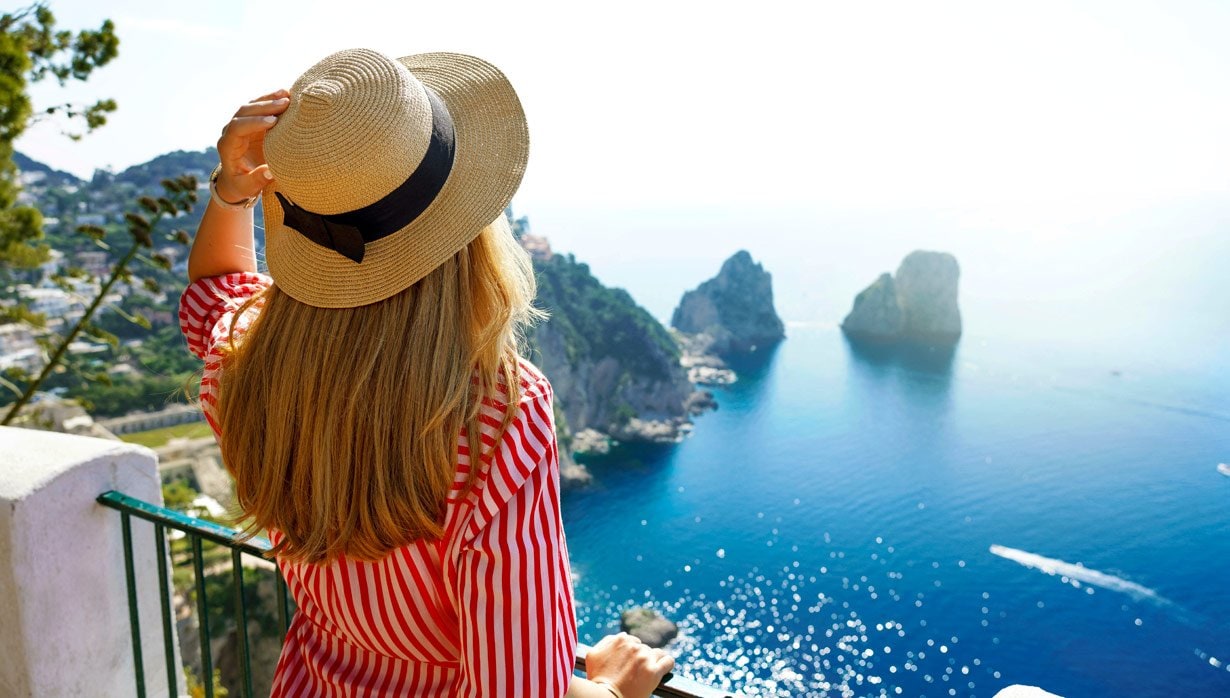 Woman in a straw hat overlooking the Faraglioni rock formations in Capri, Italy | MSC Cruises Woman in a straw hat overlooking the Faraglioni rock formations in Capri, Italy | MSC Cruises